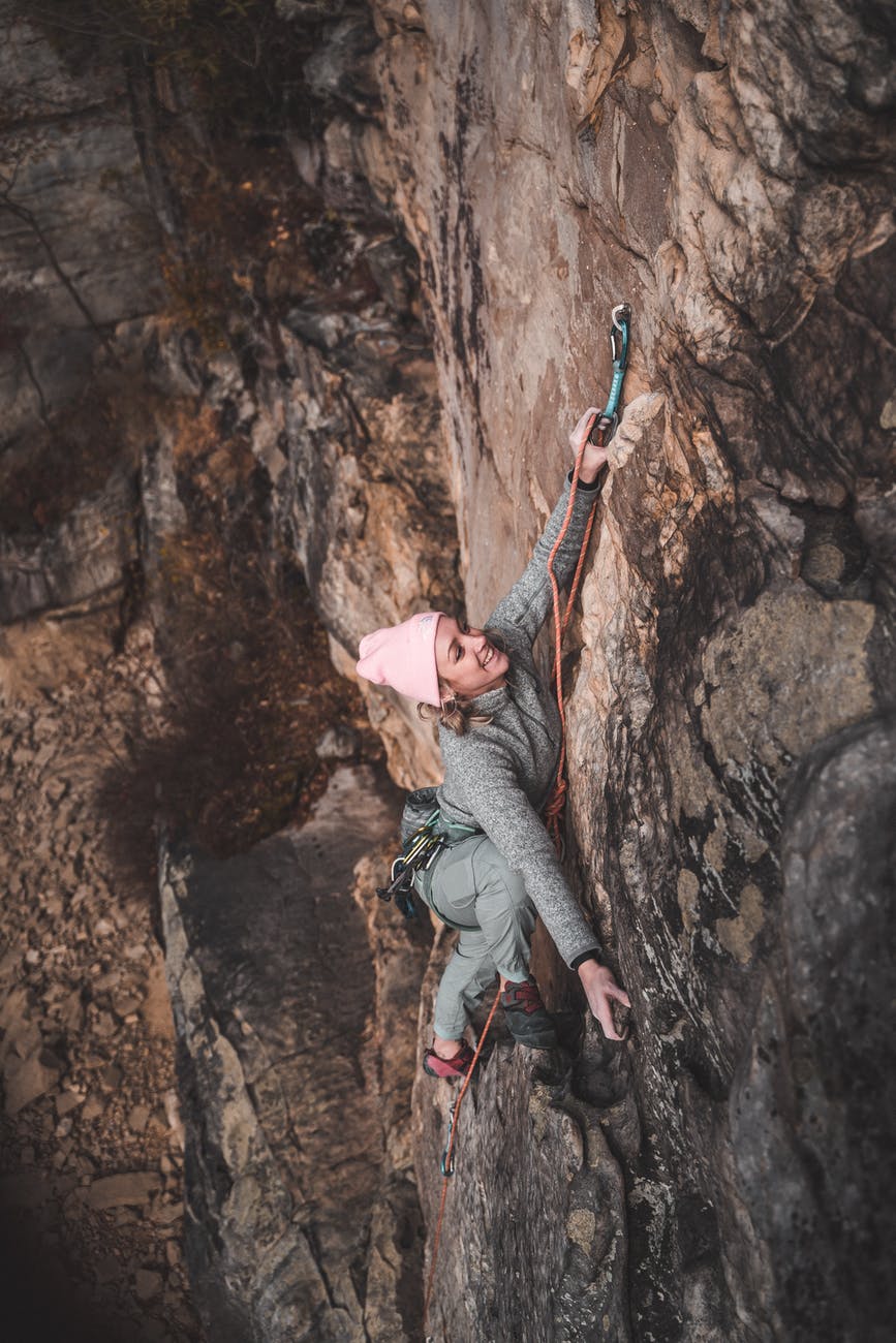 strong woman climbing up rocky mountain with rope
