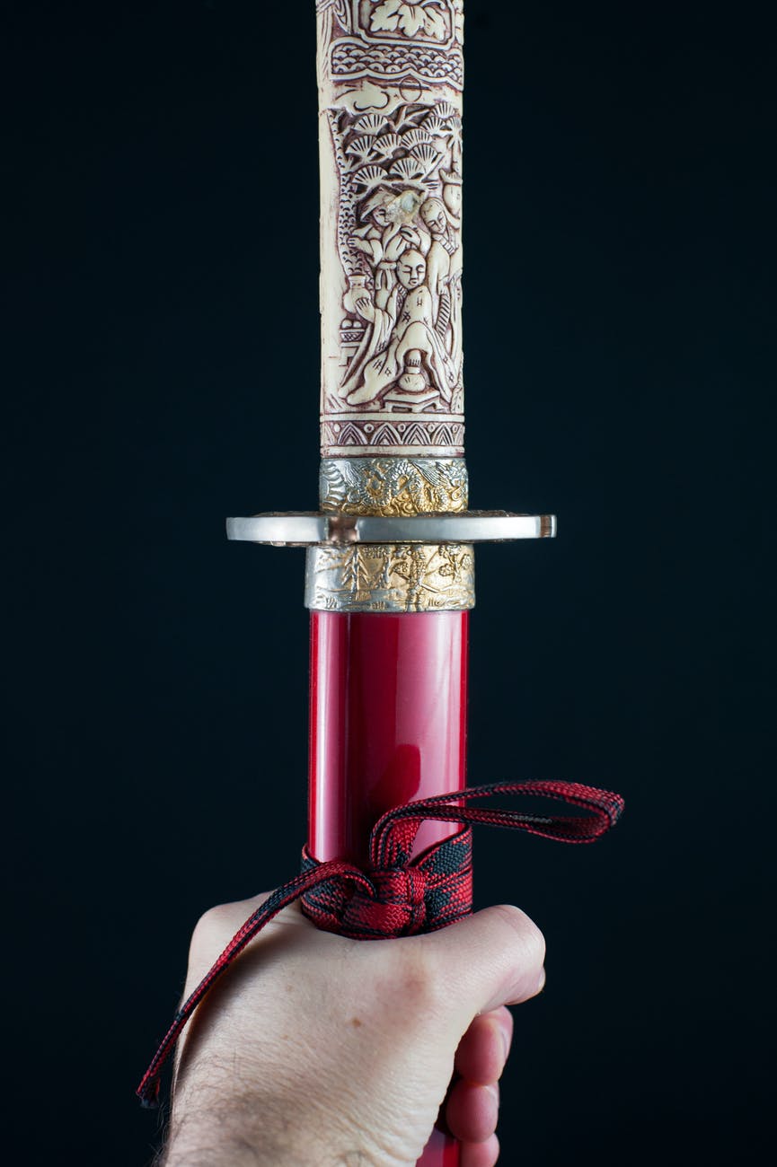 man with sword in hands on black background
