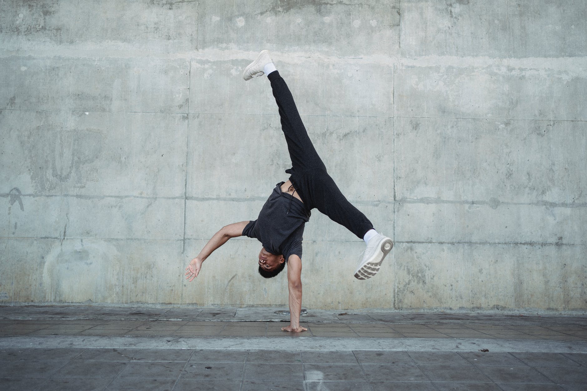 strong man breakdancing on sidewalk of city
