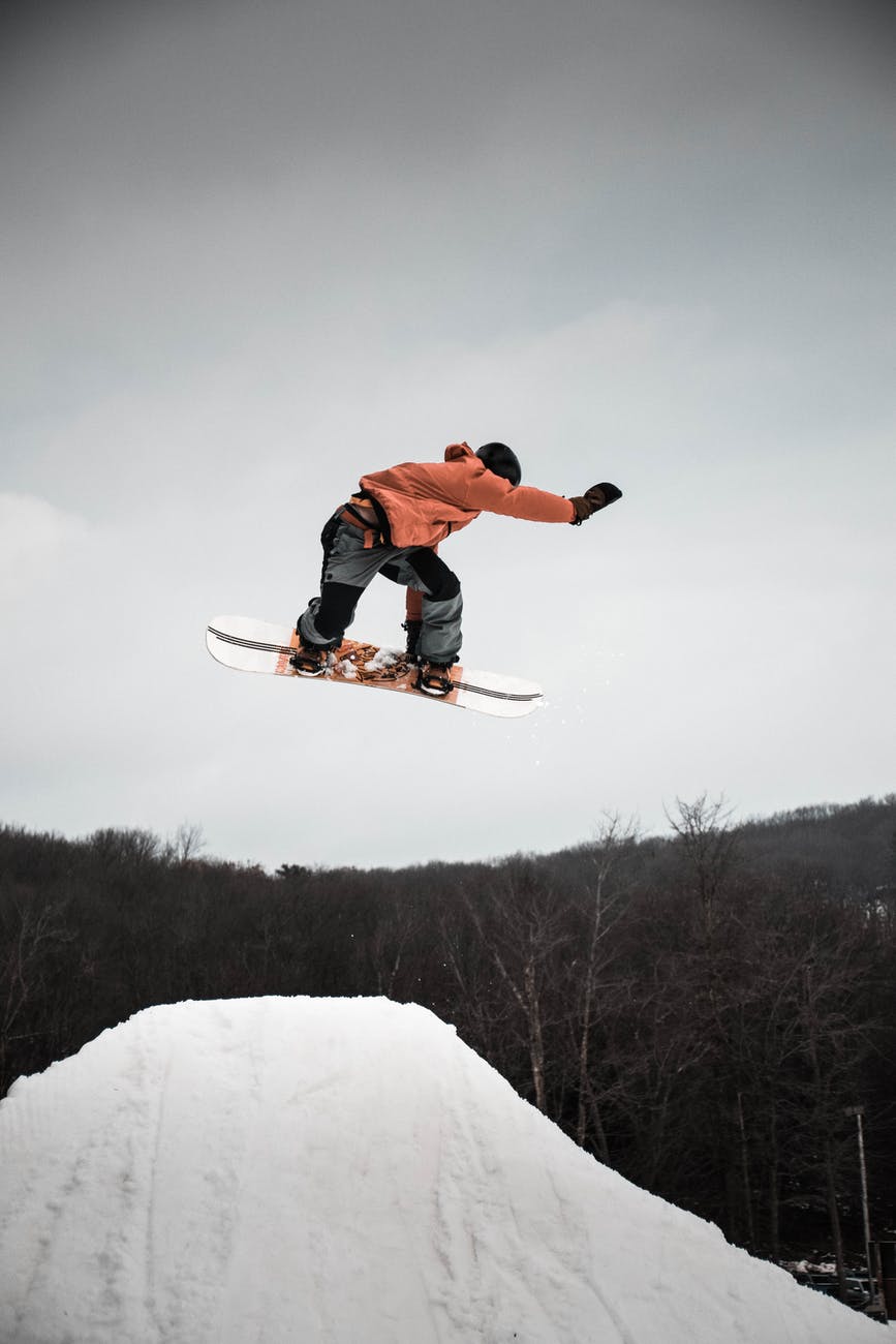 man in snowboard jumping on ramp