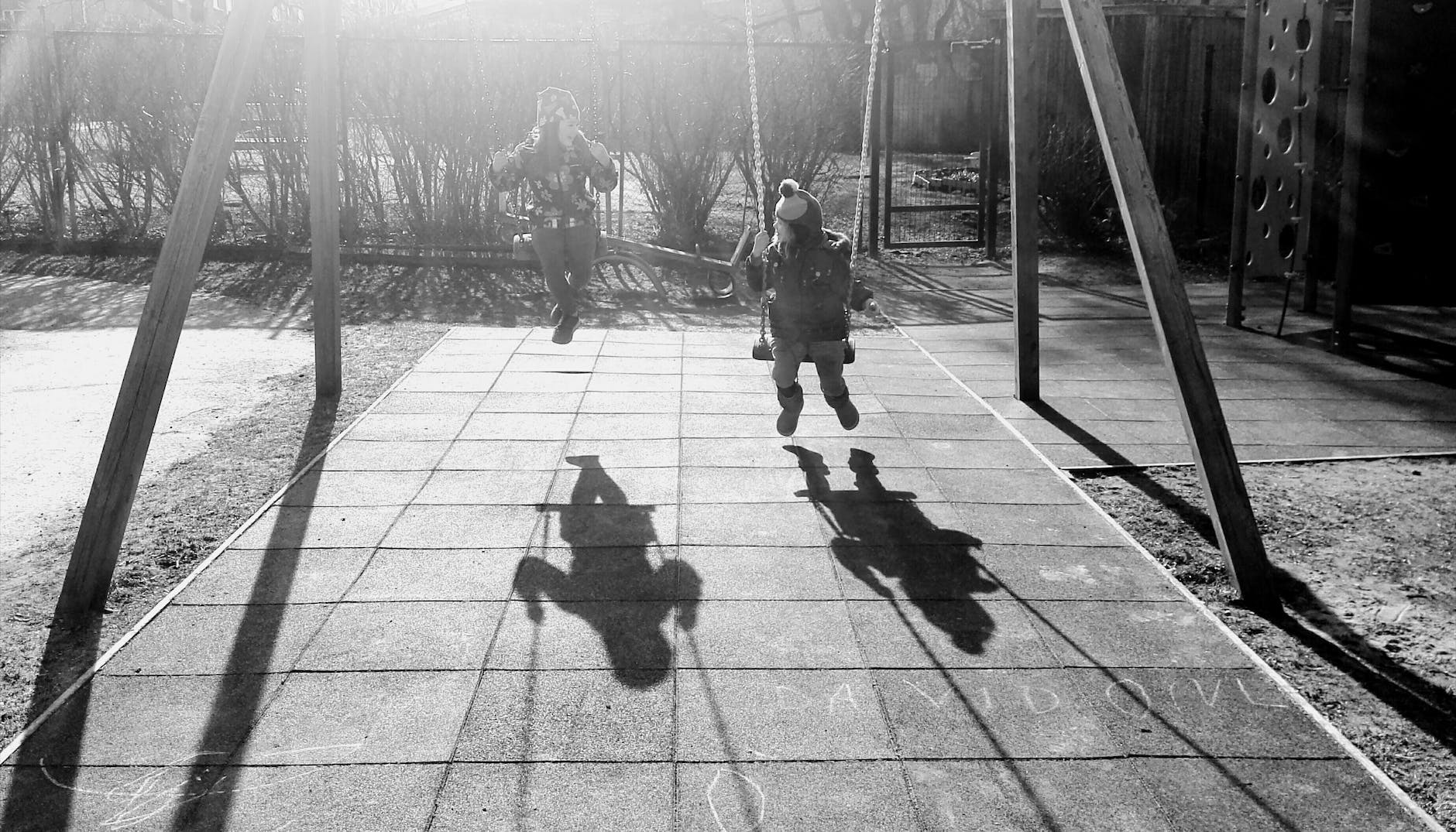 monochrome photography of children on swing